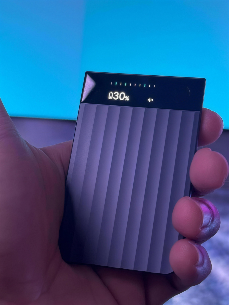 Mano che tiene il registratore PLAUD con il display che mostra il 30% di batteria